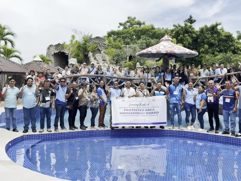 A large tour group by a resort pool holding their event banner