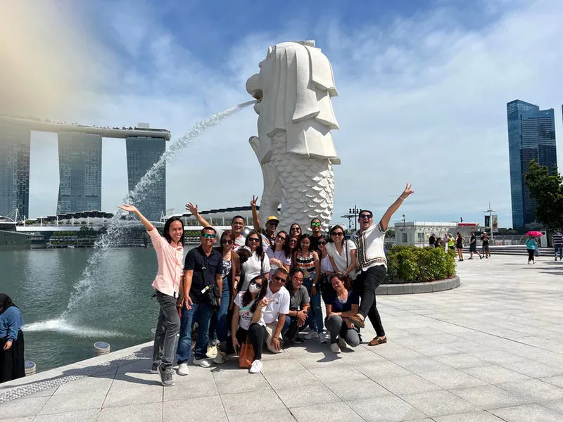 A tour group posing at the Merlion with Marina Bay Sands behind them