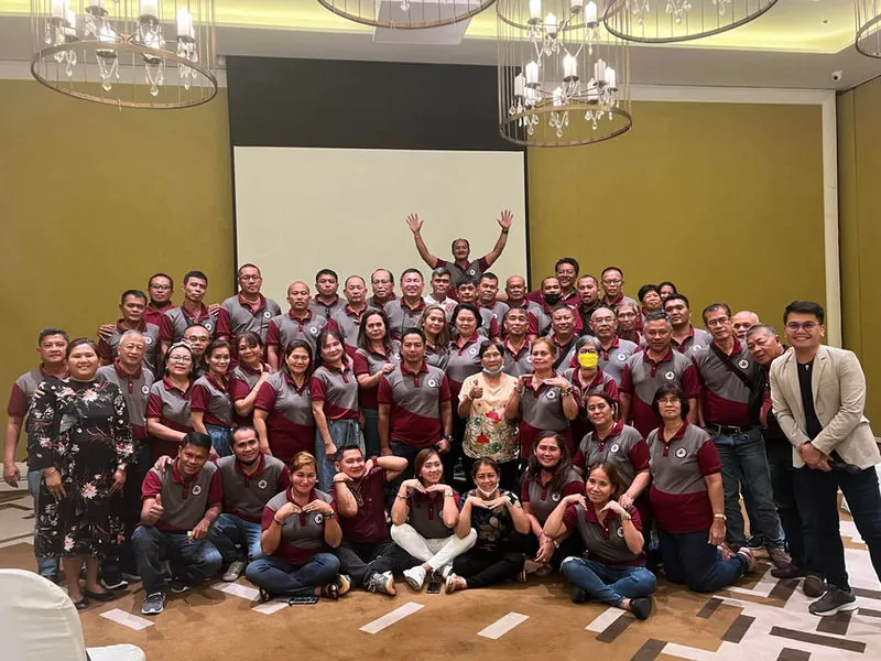 A large group of seminar participants posing together in a function room